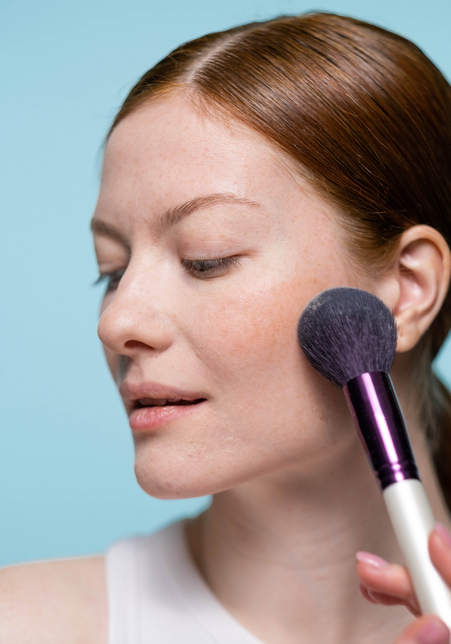 Woman applying brush to her cheek with a brush