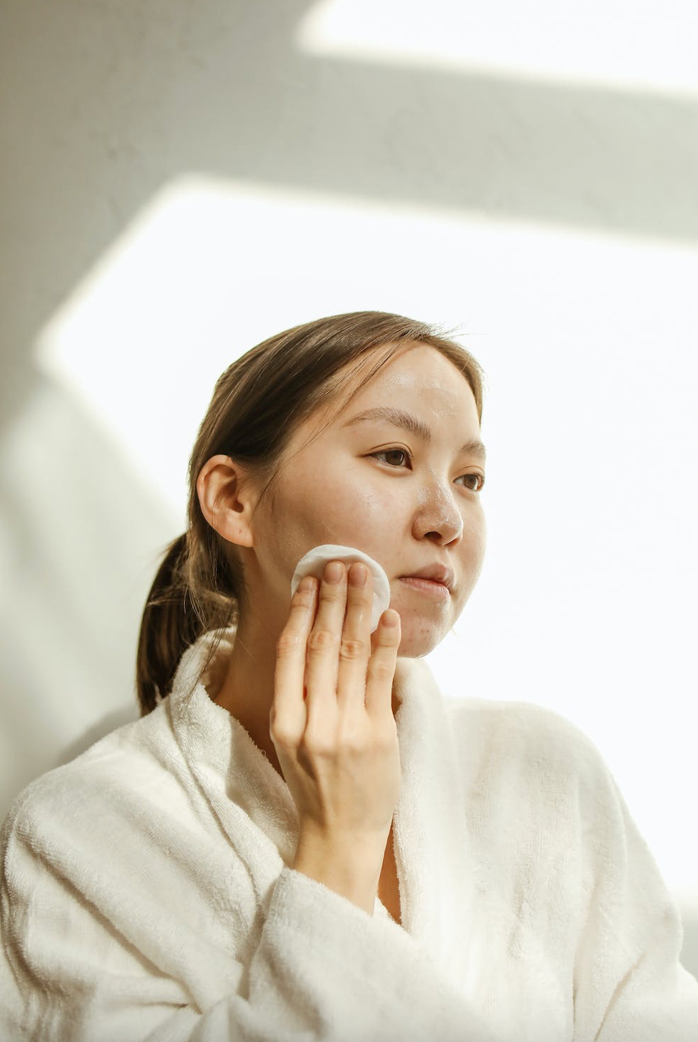 Woman wiping her face with cotton round