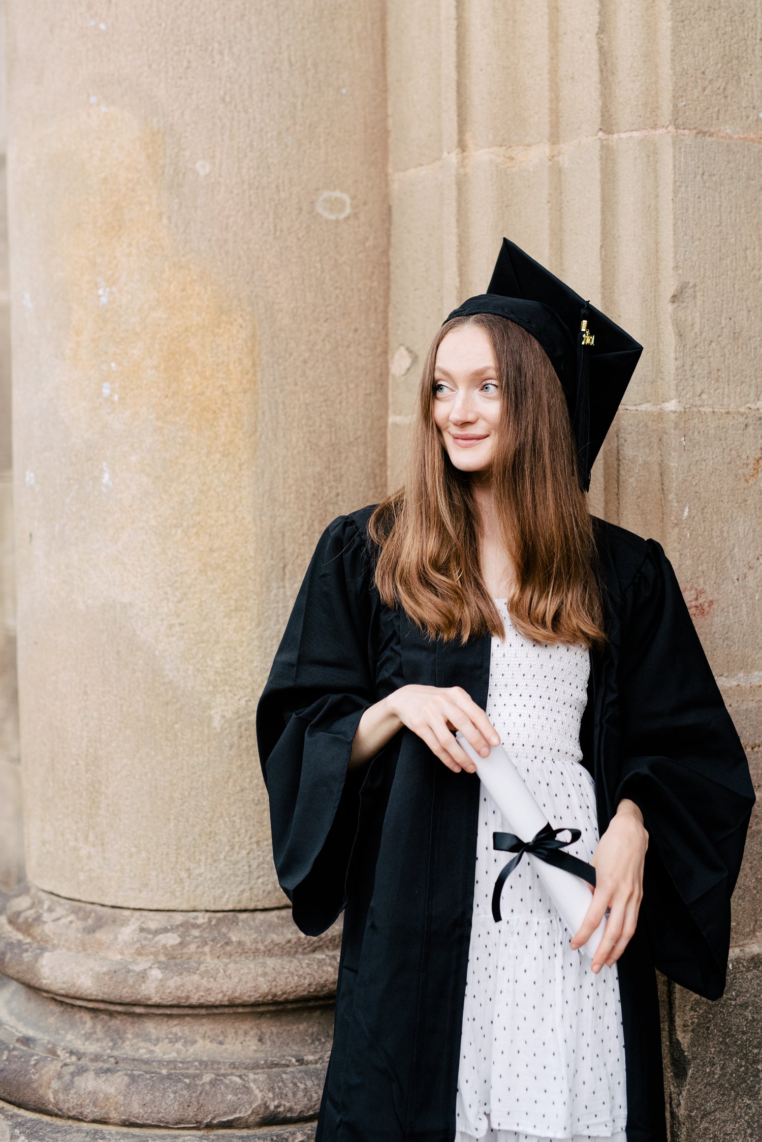 Woman who has just graduated in black academic gown smiling