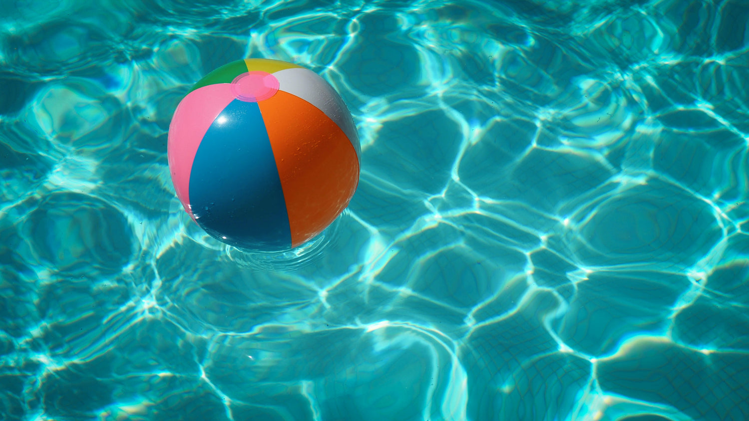 A colorful beach ball floating in a pool
